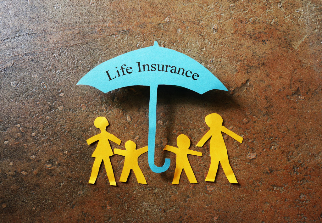 Paper family of four under a Life Insurance paper cutout umbrella