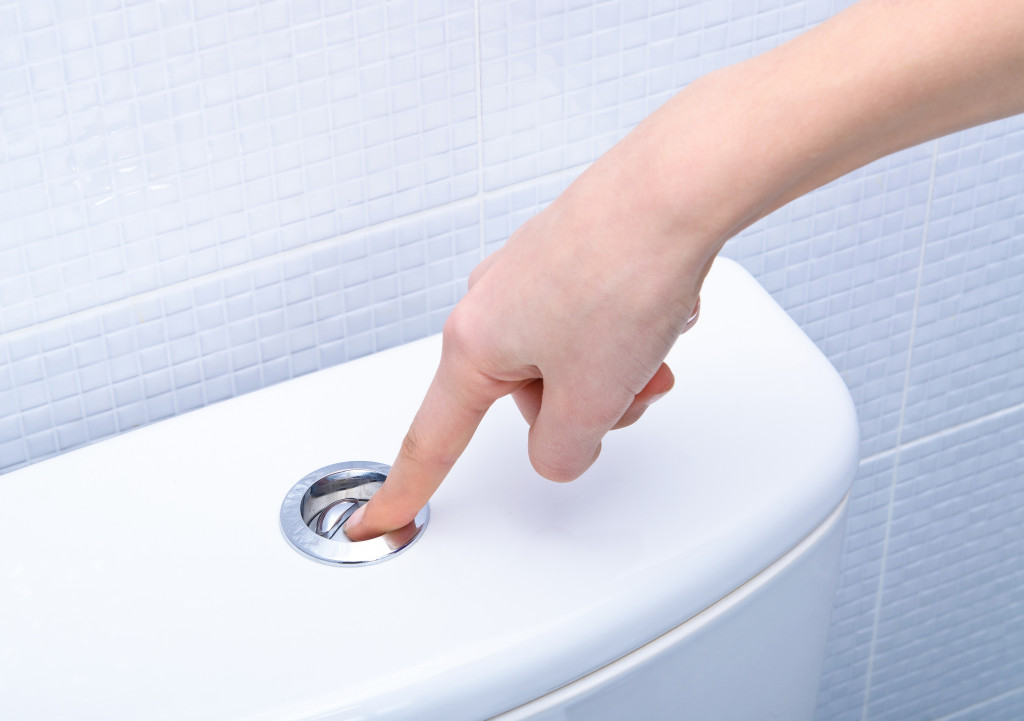 finger pushing button and flushing toilet