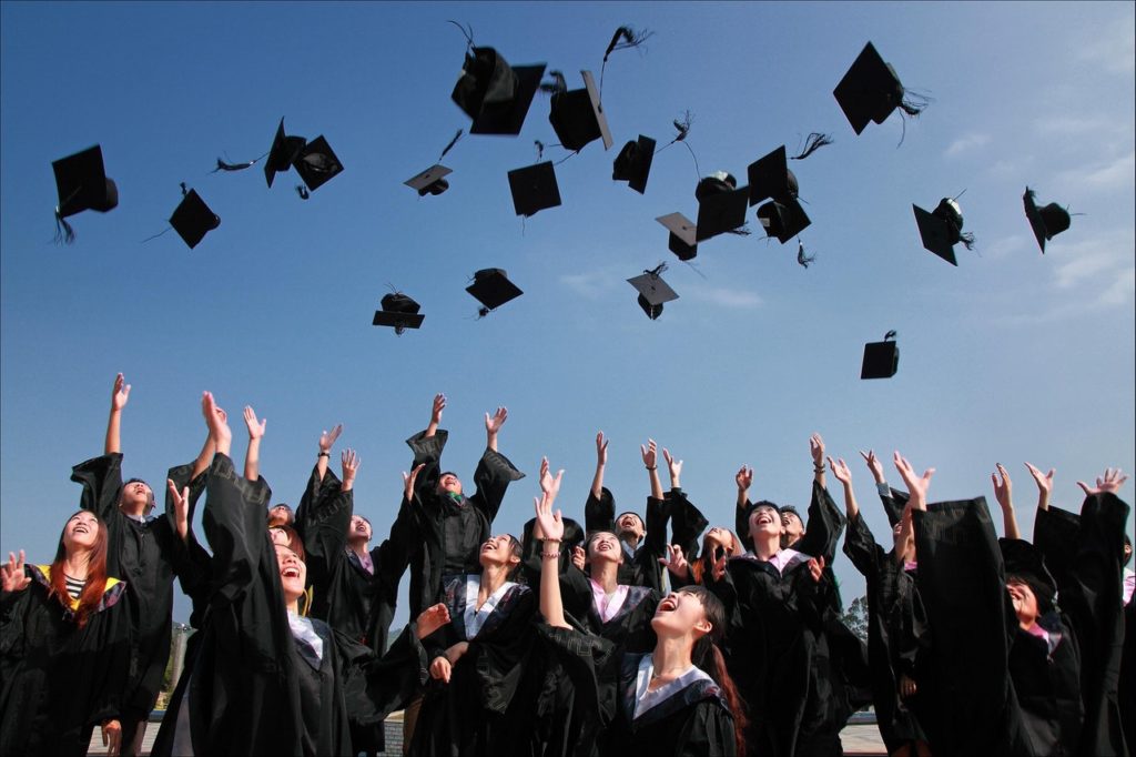 college graduates throwing their cap into the air