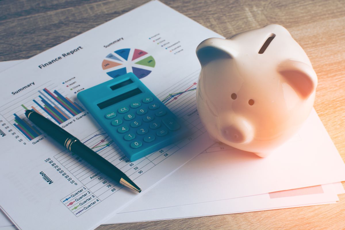 piggy bank, calculator, pen and financial report with charts