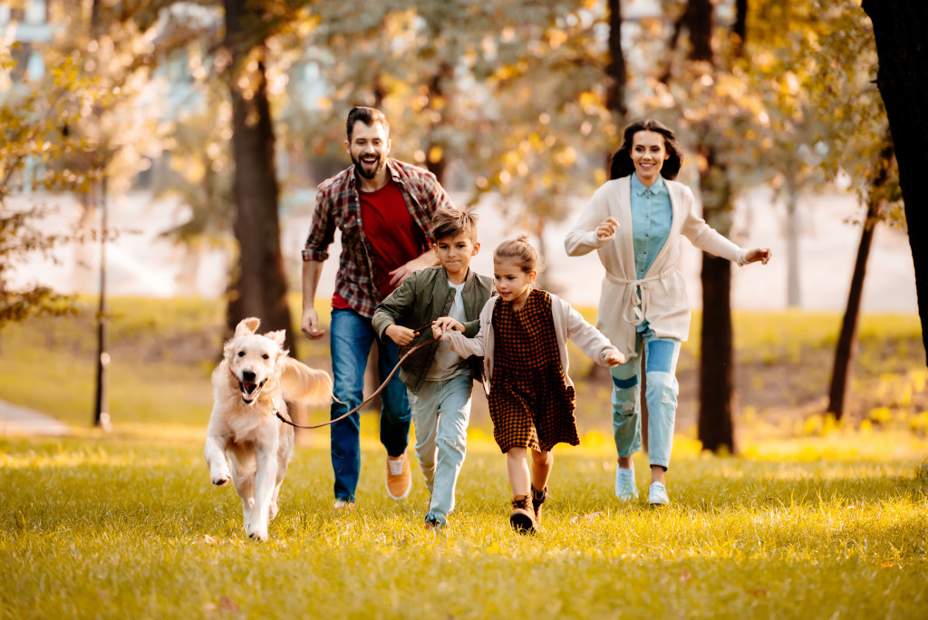 happy family running with their dog at the park