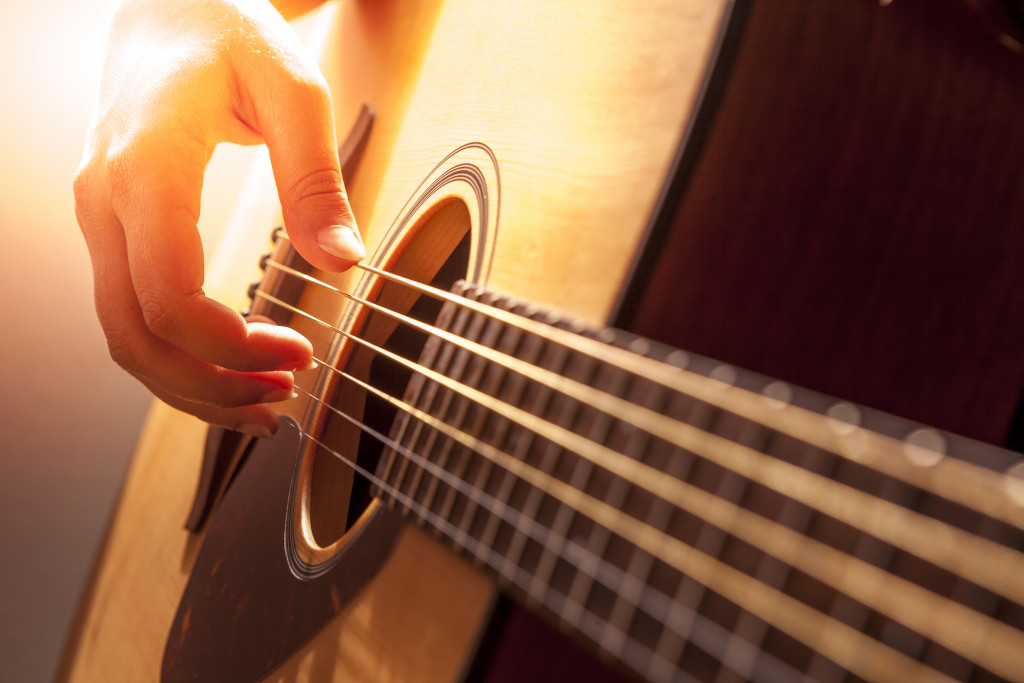 A person's hand playing an acoustic guitar