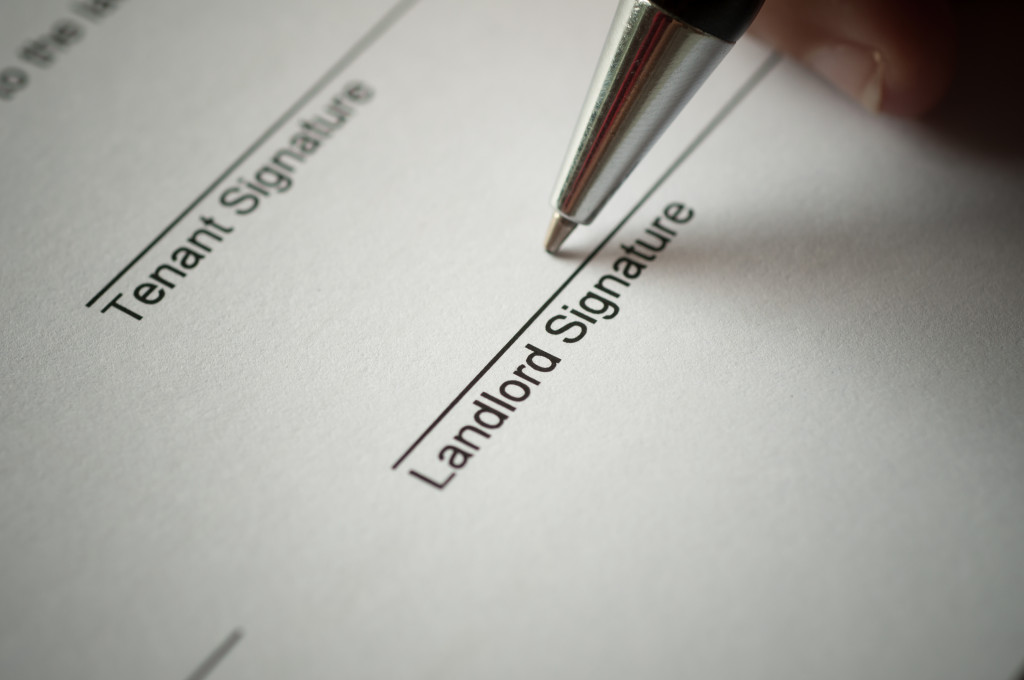 Person signing a rental agreement form using a pen