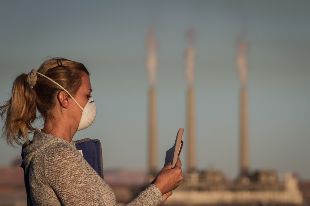 A woman reading while wearing a mask to avoid inhaling polluted air from a power plant