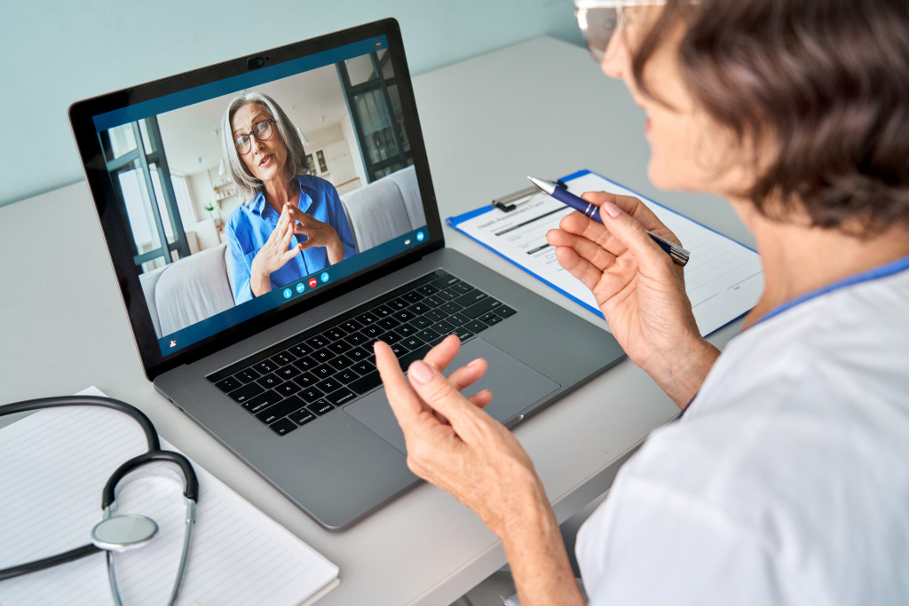 Female doctor talking with a senior patient through a videocall.