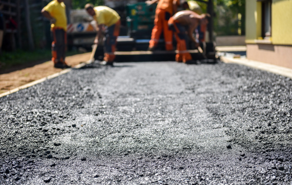Team of workers making and constructing asphalt on a road with a finisher