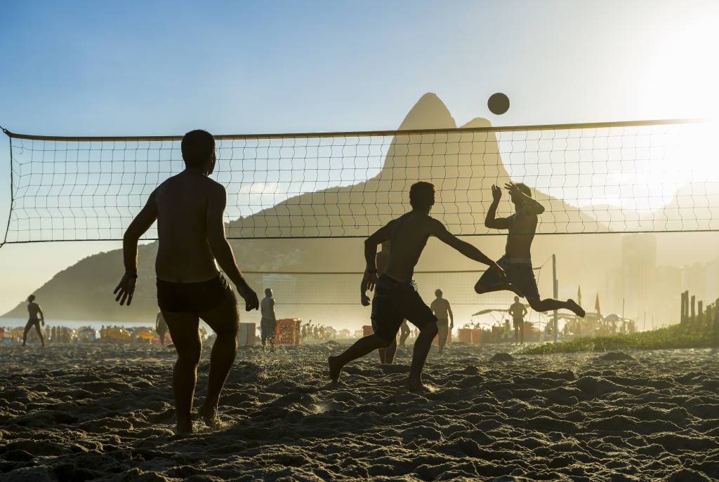 men playing beach volleyball during sunset