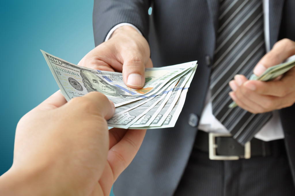 A hand receiving money from a businessman